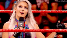 a woman in a wrestling ring is holding a microphone and talking into it .