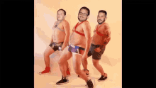 three men in underwear are dancing together and one has a tattoo on his arm