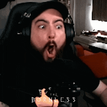 a man with a beard is wearing headphones and making a surprised face in front of a sign that says the bornless