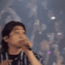 a man in a striped shirt is making a hand gesture in a crowd