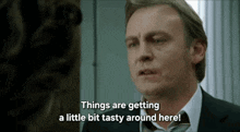 a man in a suit and tie is talking about things getting a little bit tasty around here