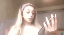 a girl with long blonde hair is holding a cell phone .