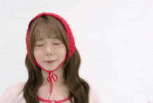 a young woman wearing a red knitted hat is making a funny face .