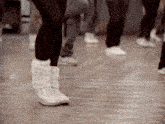 a person wearing a pair of white boots with the letter s on the bottom