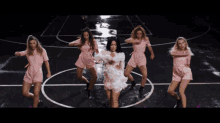 a group of women in pink jumpsuits are dancing in a circle