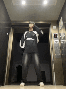 a man standing in an elevator wearing a black and white shirt with the letter y on it