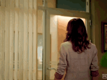 a woman standing in front of a door with the letter h on the corner
