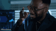 a man in a suit and glasses pointing at the camera with the hashtag #bloodshot behind him
