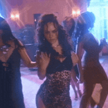 a woman in a leopard print dress is dancing with a group of women
