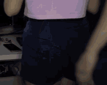 a woman in a pink shirt and blue shorts is standing in front of a computer desk .