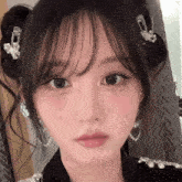 a close up of a woman 's face with earrings and a bun