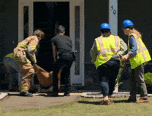 a group of construction workers are carrying a dead animal into a house