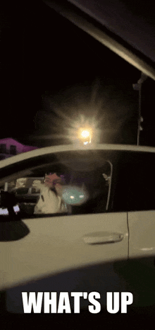 a man is driving a car at night with the words what 's up on the bottom