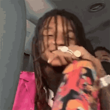 a man with dreadlocks is sitting in a car holding a bottle of water in his hand .