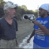 a man wearing a blue shirt that says trump is talking to another man
