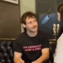 a man in a black t-shirt is sitting in a chair with a woman .