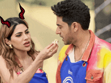 a man and a woman are standing next to each other and the woman is wearing devil horns