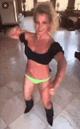 a woman in a black top and neon green bikini is dancing