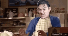 a man in an apron is making a funny face in a kitchen while holding something in his hands .