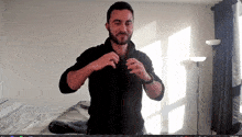 a man with a beard is standing in front of a window and a lamp
