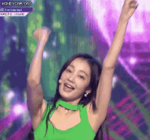 a woman in a green tank top is raising her arms in the air ..