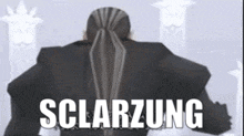 a man with a ponytail is standing in front of a white background with the word sclarzung written on it .