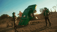 a group of people standing in front of a green car
