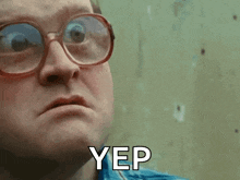 a man wearing glasses and a blue shirt says yep on his face