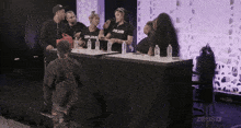 a group of people standing around a table with zeus written on the front of their shirts
