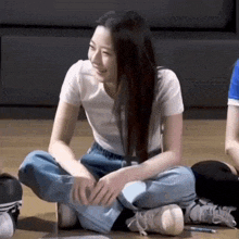 a girl is sitting on the floor with her legs crossed and smiling