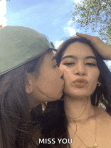 a woman kissing another woman on the cheek with the words miss you above them