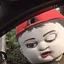 a close up of a mascot wearing a red hat and smoking a cigarette .