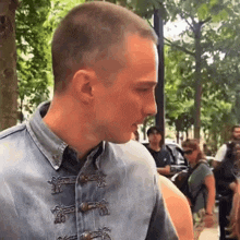 a man wearing a denim shirt with buttons on the front is walking down a street