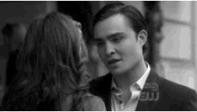 a black and white photo of a man and a woman looking at each other