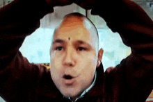 a man with a black spot on his face is making a heart shape with his hands