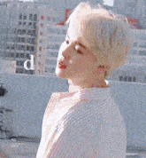 a young man with blonde hair and red lips is standing on a rooftop .