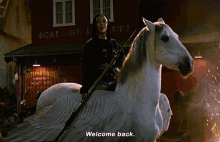 a woman is riding on the back of a white horse with the words welcome back