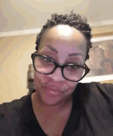 a woman wearing glasses and a black shirt making a funny face