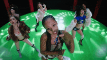a group of women are dancing in a circle on a green background