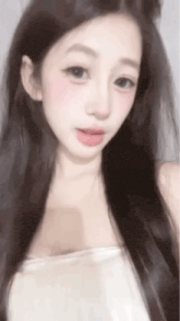 a close up of a woman 's face with long hair and a white shirt .