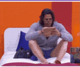 a man is sitting on a bed looking at a tablet with edairan written on the bottom