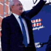 a man in a suit and tie is holding a microphone in front of a blue background .