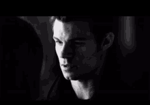 a black and white photo of a man and woman looking at each other .
