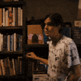 a man is standing in front of a bookshelf with a book titled truth about a strange story on it