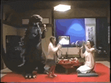 a group of people are playing a video game with a monster in the background