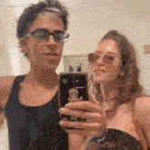 a man and a woman are taking a selfie together in a bathroom .