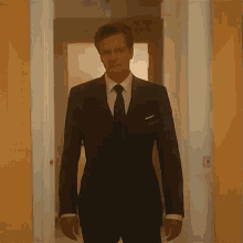 a man in a suit and tie is standing in a hallway and looking at the camera .