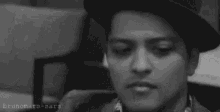 a black and white photo of a man wearing sunglasses , a hat and a shirt .