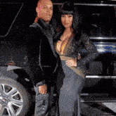 a man and woman are posing for a picture in front of a black suv