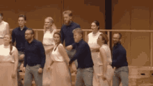 a group of people are standing on a stage holding hands .